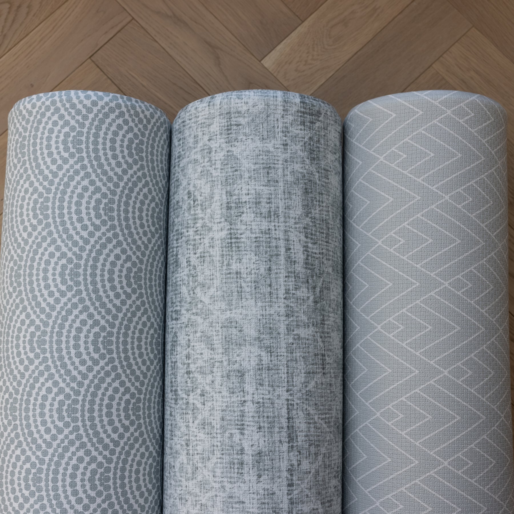 Grey playmats rolled up. Soft squishy baby and toddler mats with interior style designs