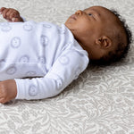A baby lying on a soft Acorn design Totter + Tumble modern nursery playmat
