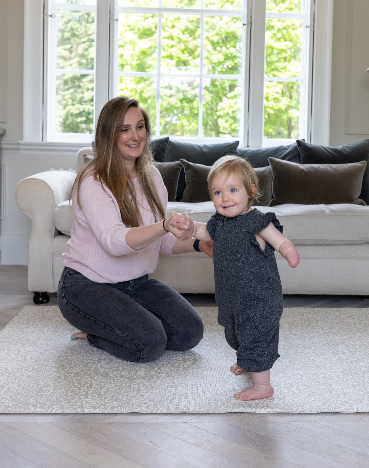 A mum and toddler play together in the living room on a soft luxury padded play mat.