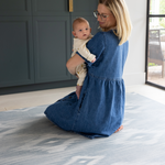 Mother holding baby on Large baby play mat in one piece to unroll in the home squishy memory foam surface to keep floor time comfortable and supported