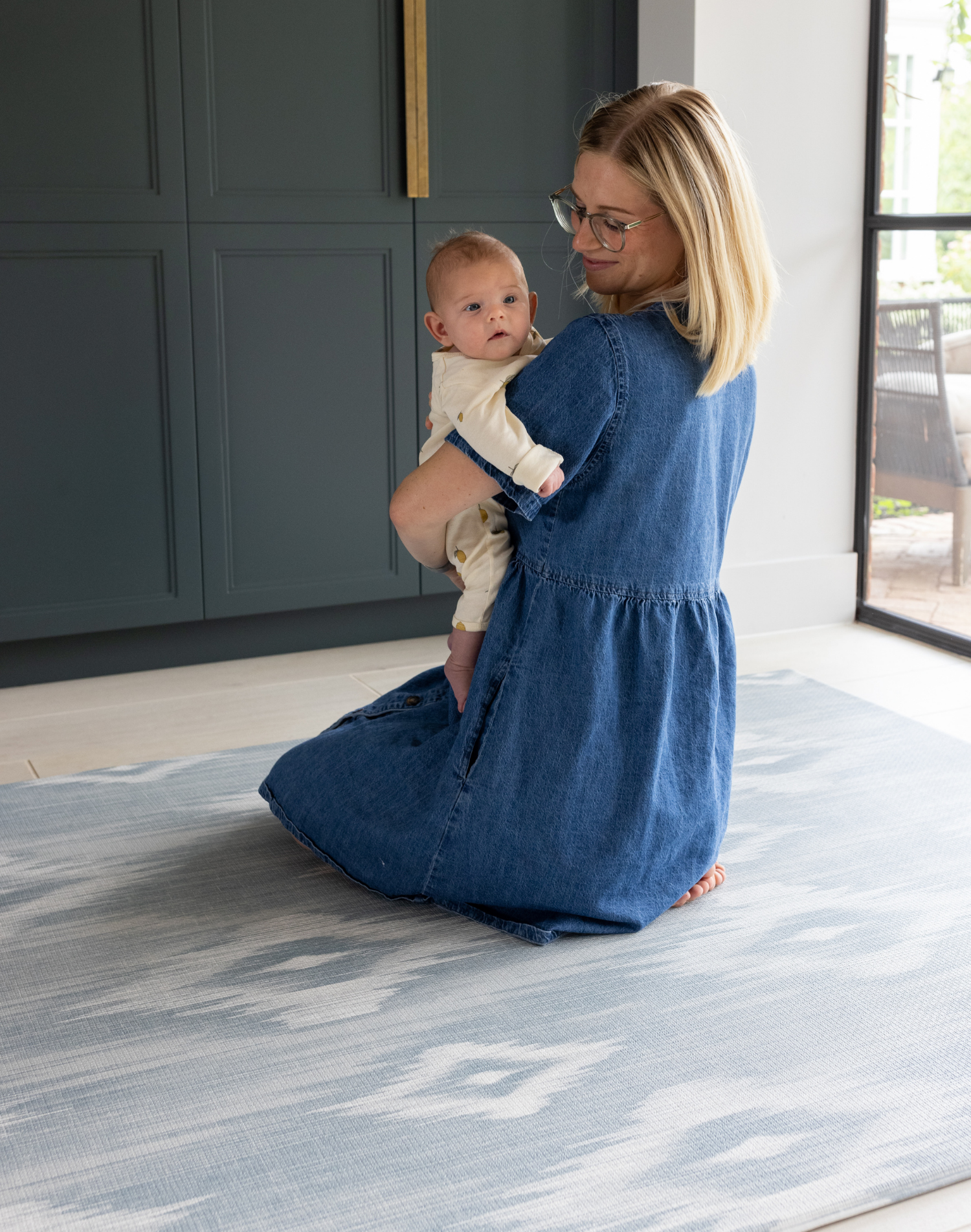 Mother holding baby on Large baby play mat in one piece to unroll in the home squishy memory foam surface to keep floor time comfortable and supported