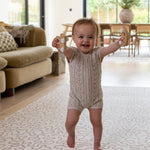 Toddler playing on The Brecon, a large play mat for crawling baby and walking toddler in a neurtal red colour palette