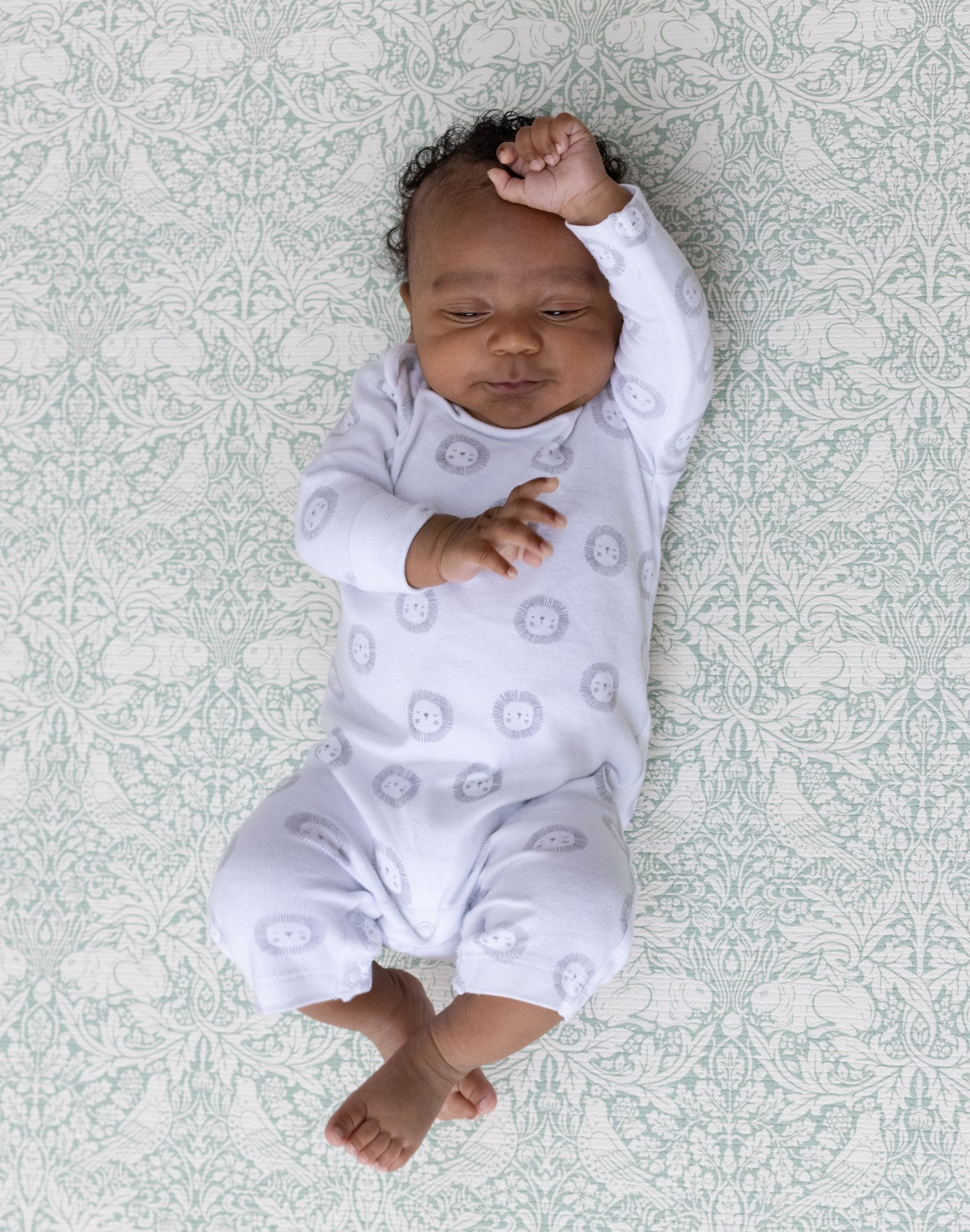 Baby relaxes on The Brer Rabbit Playmat with floral heritage prints, ideal for soft aesthetic spaces.