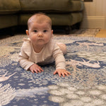 Baby enjoys tummy time on a Totter + Tumble luxury foam play mat in a William Morris botanical design - a non-toxic, stylish baby essential for modern nurseries.
