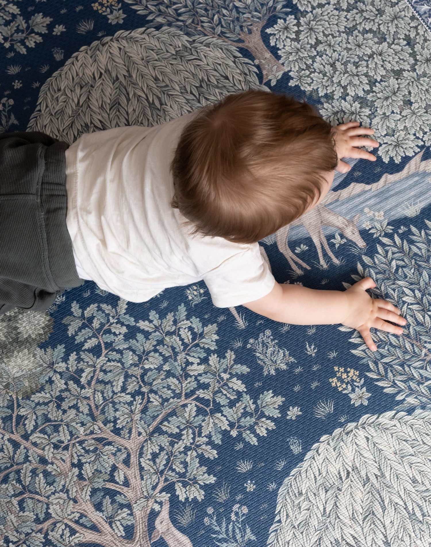 Bird’s-eye view of a baby exploring a William Morris decorative play mat - functional nursery decor meets elegant baby room ideas