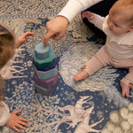 Children play with wooden stacking toys on a botanical-patterned playmat by Totter + Tumble - the perfect mix of safe play and designer nursery decor.