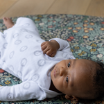 totter and tumble round size playmat in blackthorn morris& co print padded non toxic foam for kids baby lying on playmat happy child