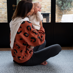 Mother holds baby sitting comfortably on the antibacterial playmat by totter and tumble