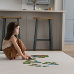 Little girl enjoys putting together a puzzle on the protective Globe Trotter floor mat that supports and cushions