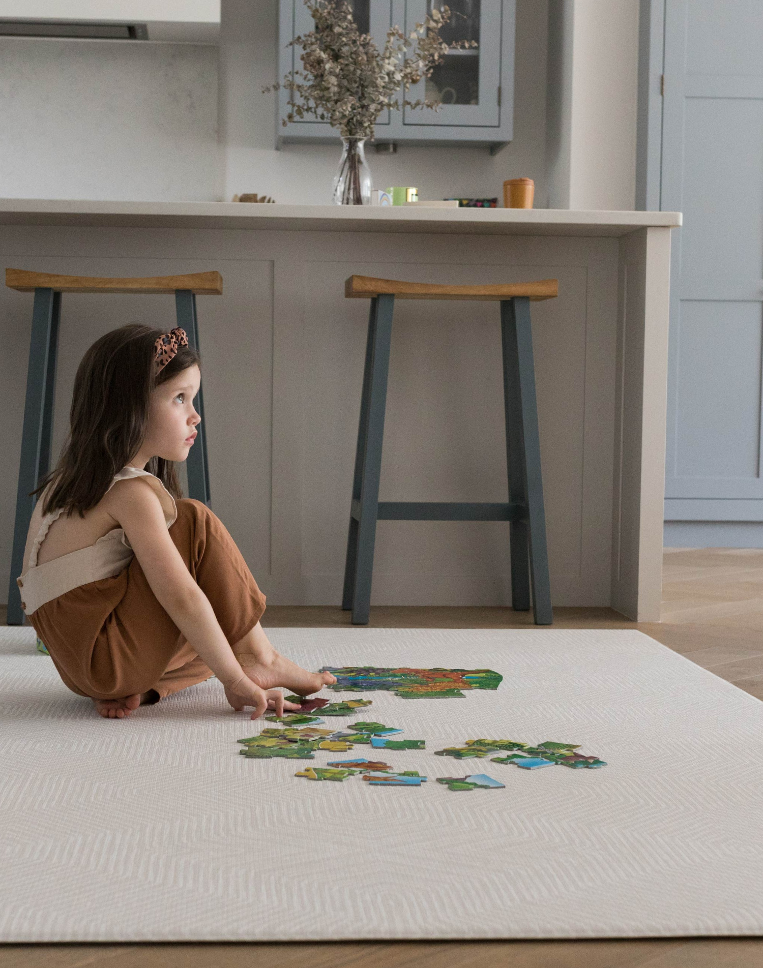 Little girl enjoys putting together a puzzle on the protective Globe Trotter floor mat that supports and cushions