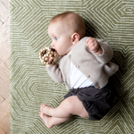 Baby rolls over on a textured baby mat that offers support for play time and development