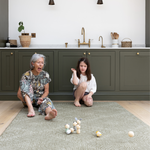 Grandmother and child sit on a large kitchen mat that has a modern kilim textile design to complement the interior