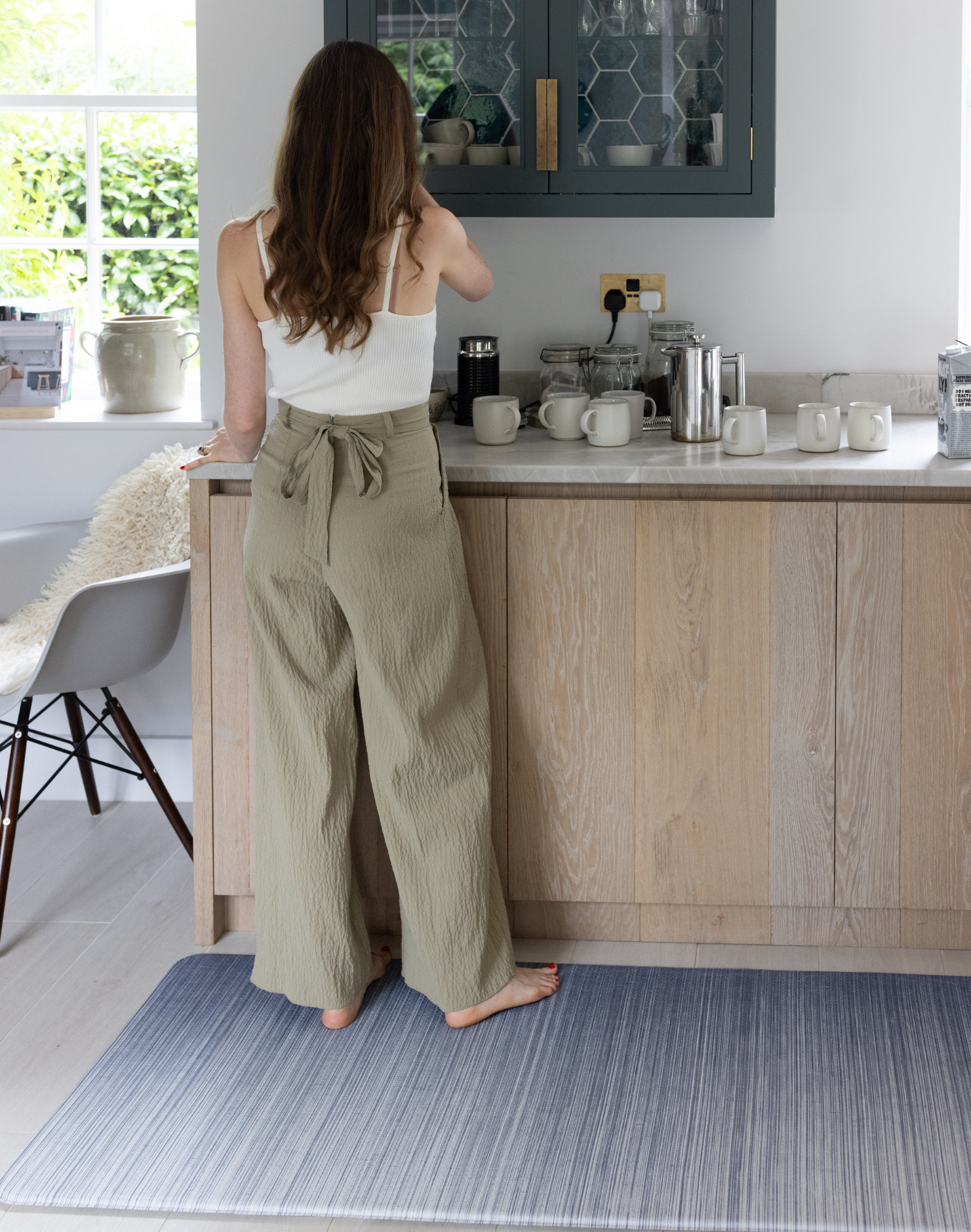 Lady stands on anti fatigue mat in kitchen with beautiful gradient design the Kasuri complements modern family decor