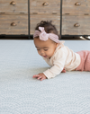 Baby lays on tummy on floor mat interested in the beautiful scalloped motif inspired by Japanese Seigaiha waves