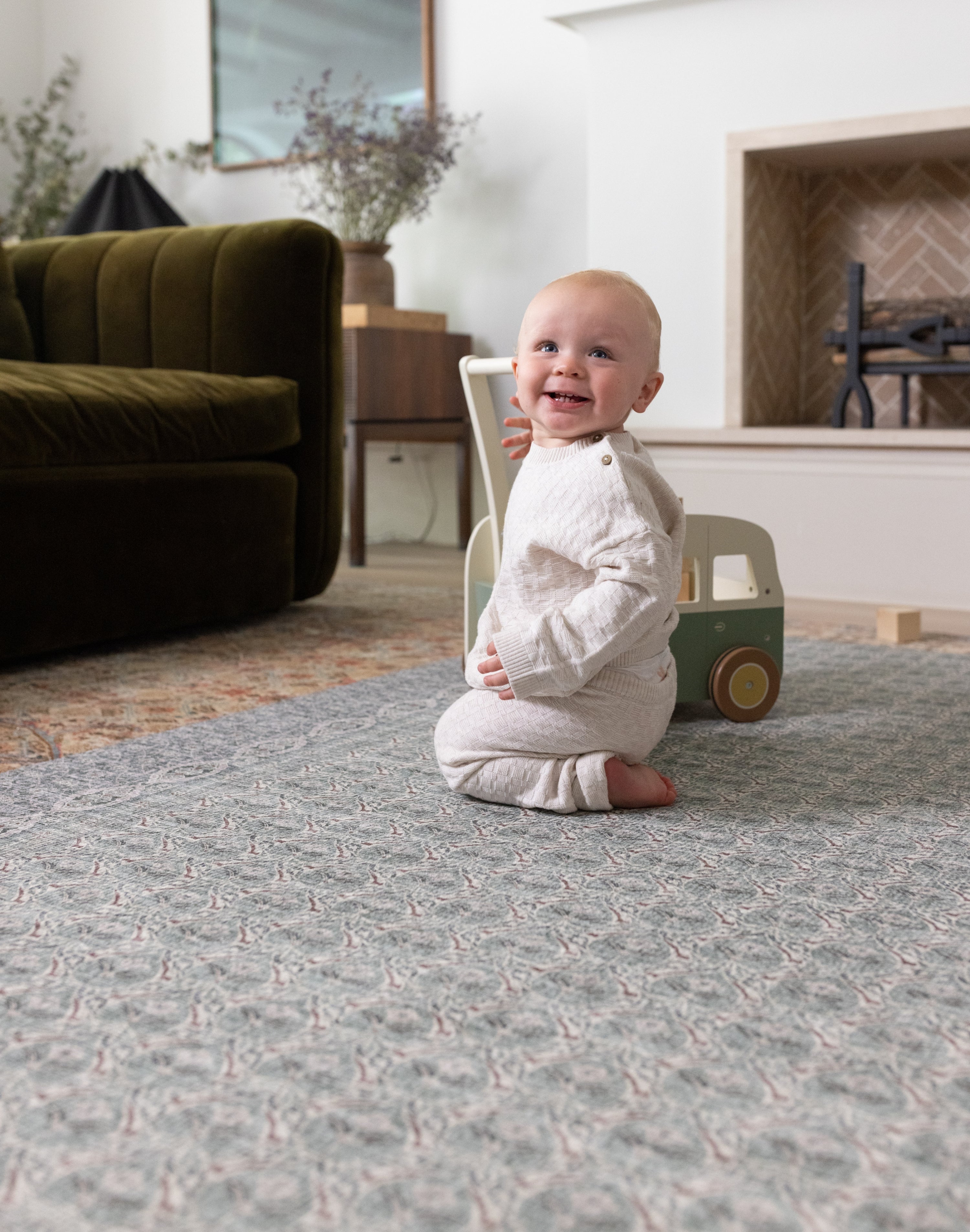 Happy baby playing on a large playmat in a stylish interior setting