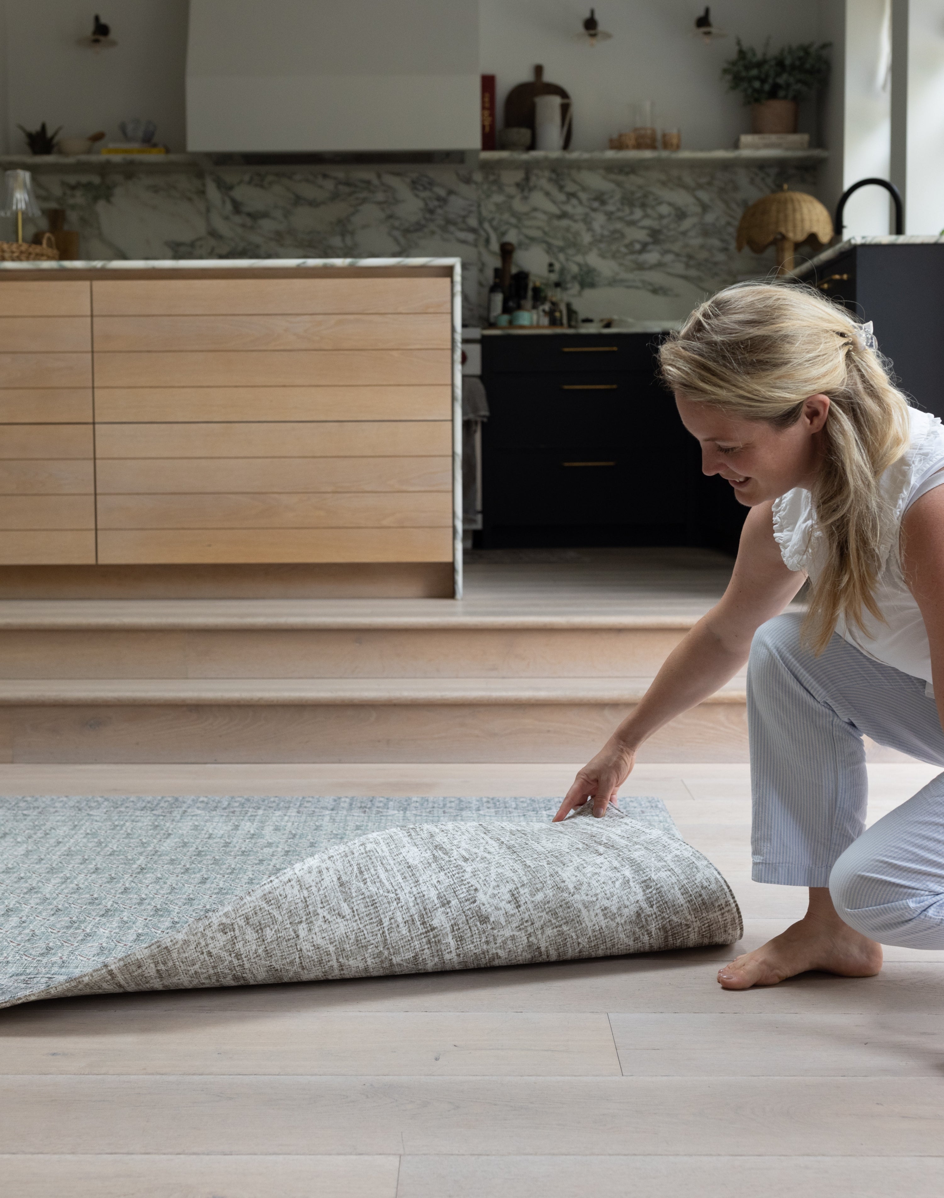 Woman unrolling a double sided playmat on a wooden floor in a modern kitchen