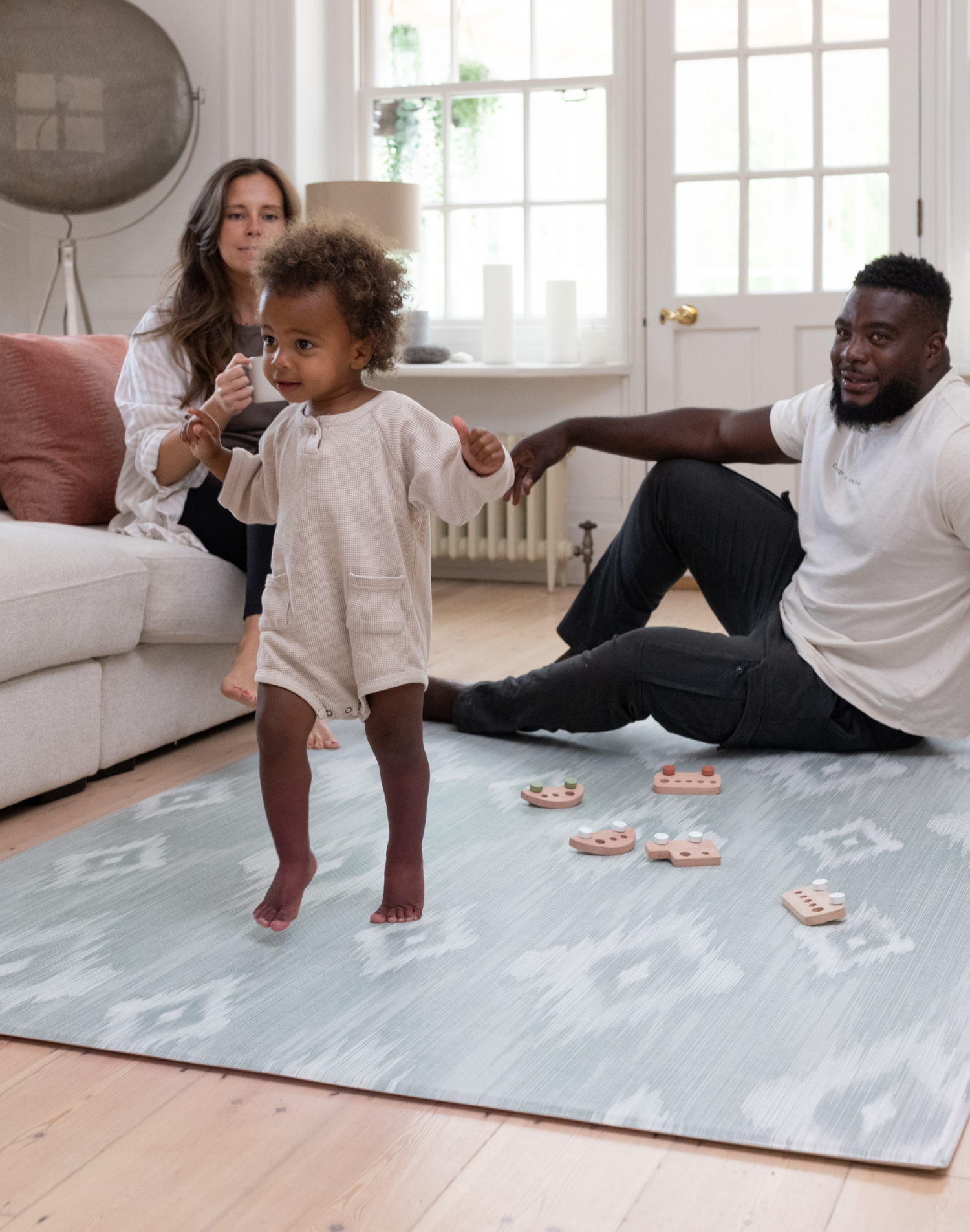 Mother father and baby enjoy floor time on Simple baby play mat in stylish ikat design perfect for family homes in subtle green and grey design