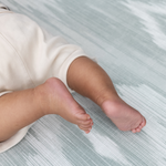 Close up of baby feet on thick baby play mat made with safe materials and memory foam use from birth and enjoy for all of the developmental milestones