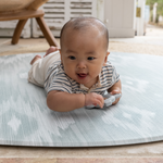 Adorable baby enjoys tummy time on thick and large baby round play mat perfect for floor time for the whole family
