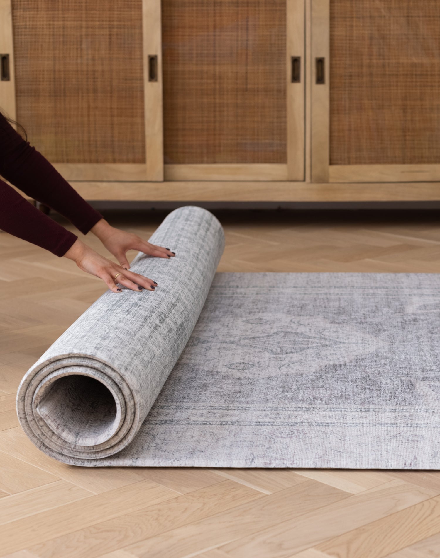 Hands roll out a rug-like baby playmat that has two elegant designs on either side