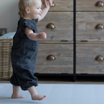 Toddler holds adults hand and walks across textured memory foam playmat