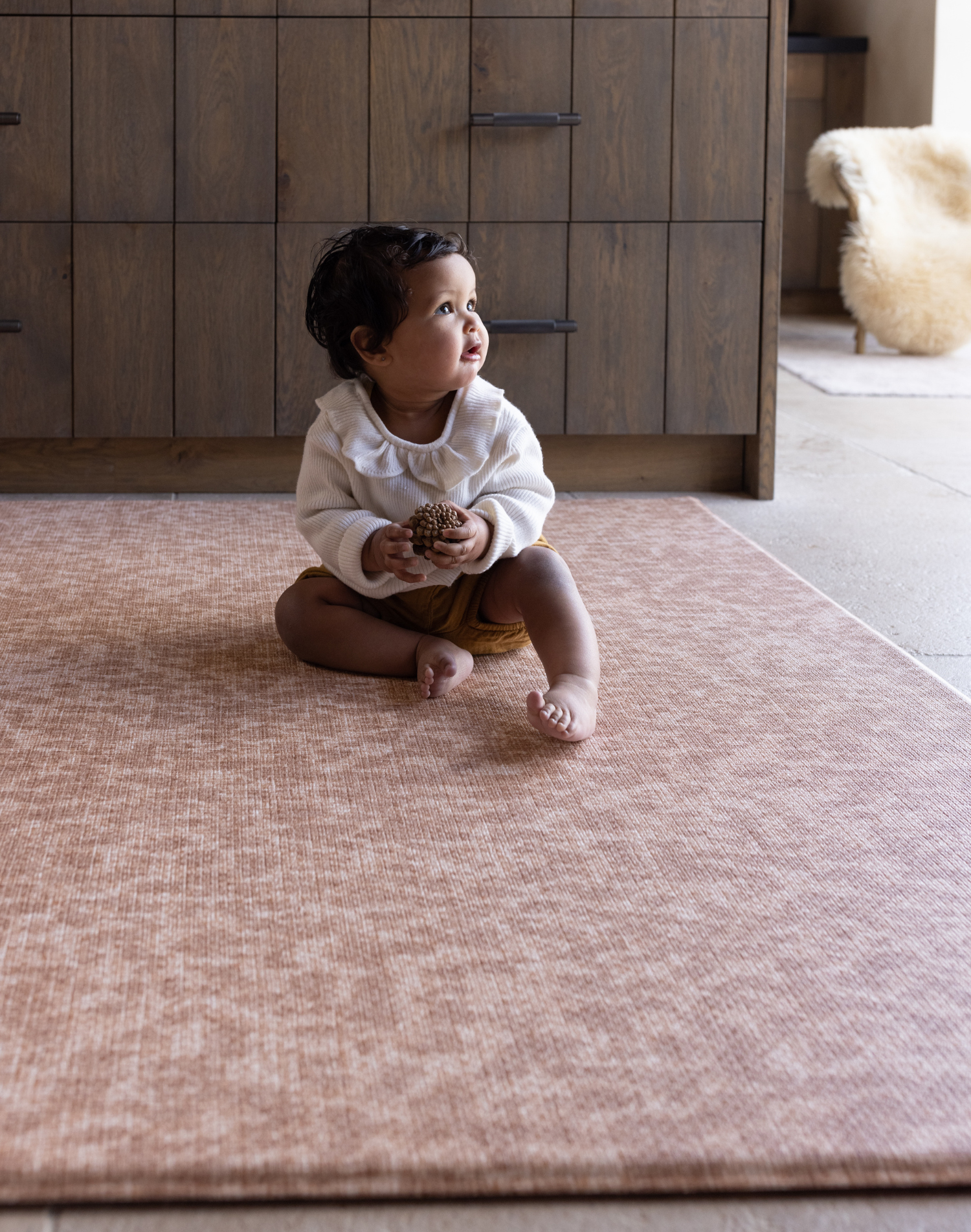 Baby sitting unaided and in comfort on the warm sand orange play mat the Rusa with a textural animal print design