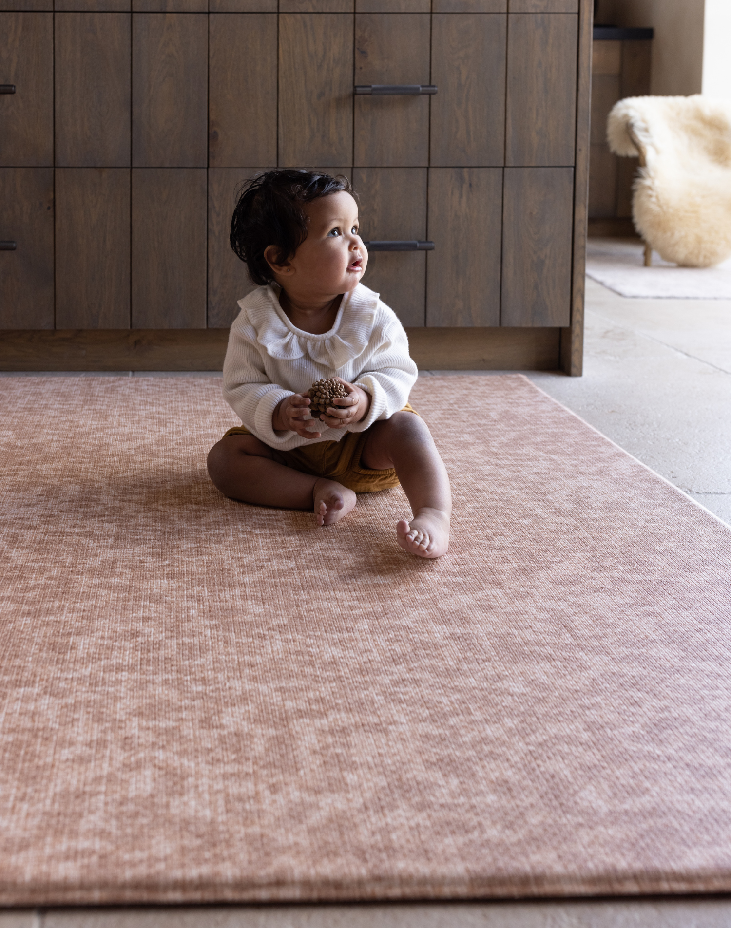 Baby sitting unaided and in comfort on the warm sand orange play mat the Rusa with a textural animal print design