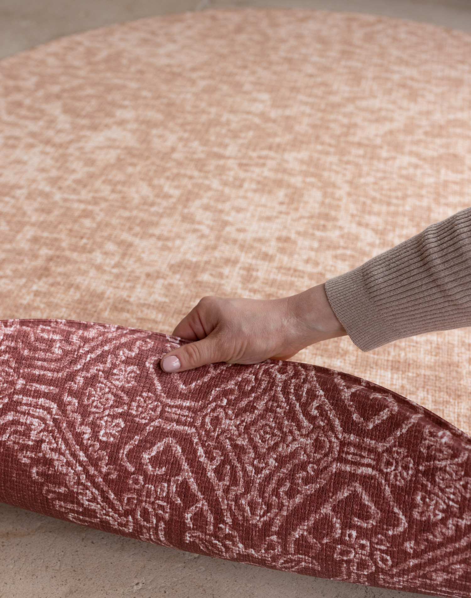 Hand pulls back edge of double sided memory foam playmat The Rusa and The Merah thick memory foam allows for comfort in the family homes with two motifs to complement modern home interiors