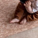 Baby sits unaided on protective memory foam playmat the Rusa featuring a delicate animal print motif that complements modern homes
