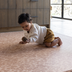 Baby plays with pinecone on orange leopard print play mat the Rusa a beautiful modern play mat design which provide comfort and protection on hard flooring around the home