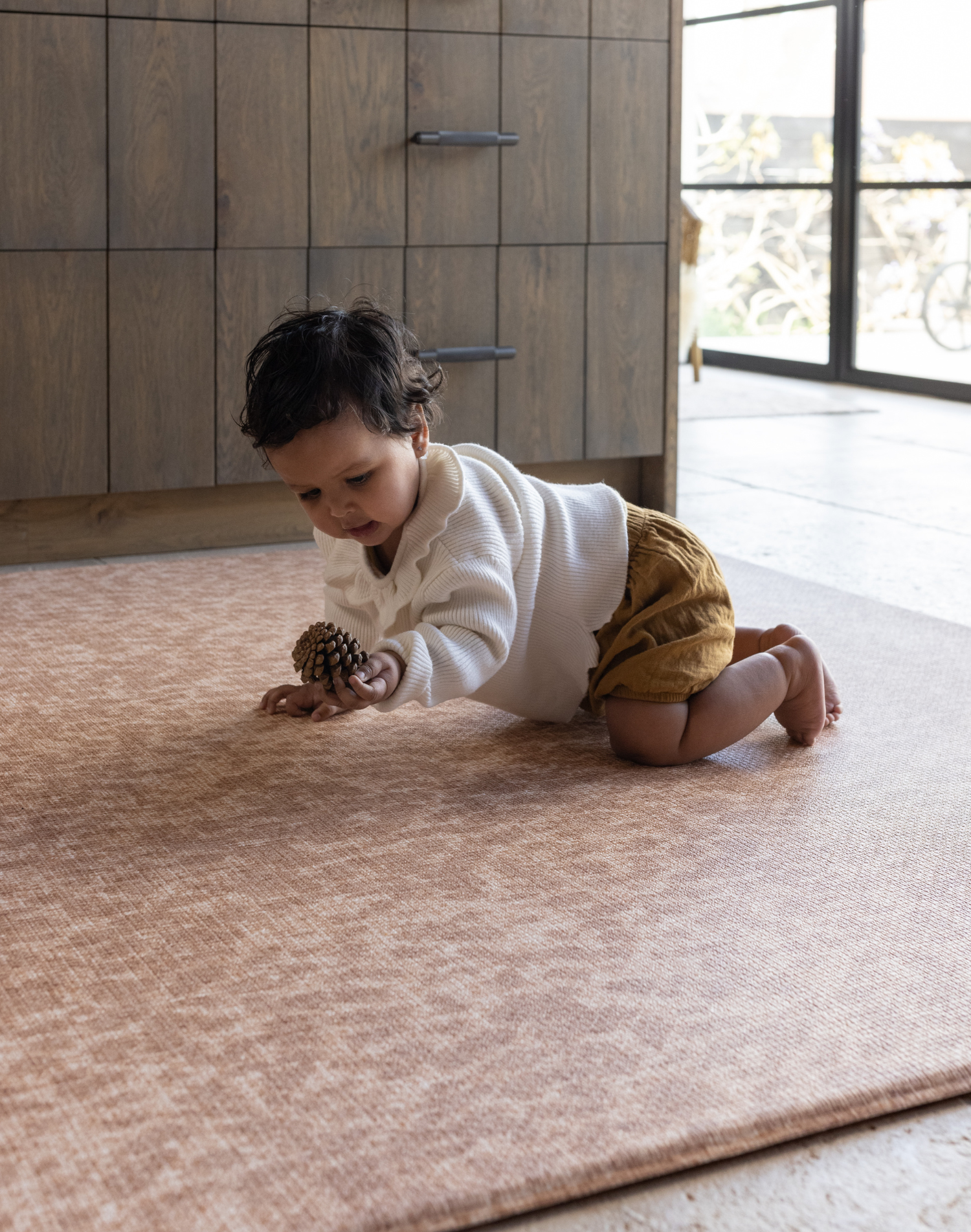 Baby plays with pinecone on orange leopard print play mat the Rusa a beautiful modern play mat design which provide comfort and protection on hard flooring around the home