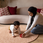 Baby and mother play on round orange play mat the Rusa with a delicate animal skin motif that looks stylish against modern furnishings