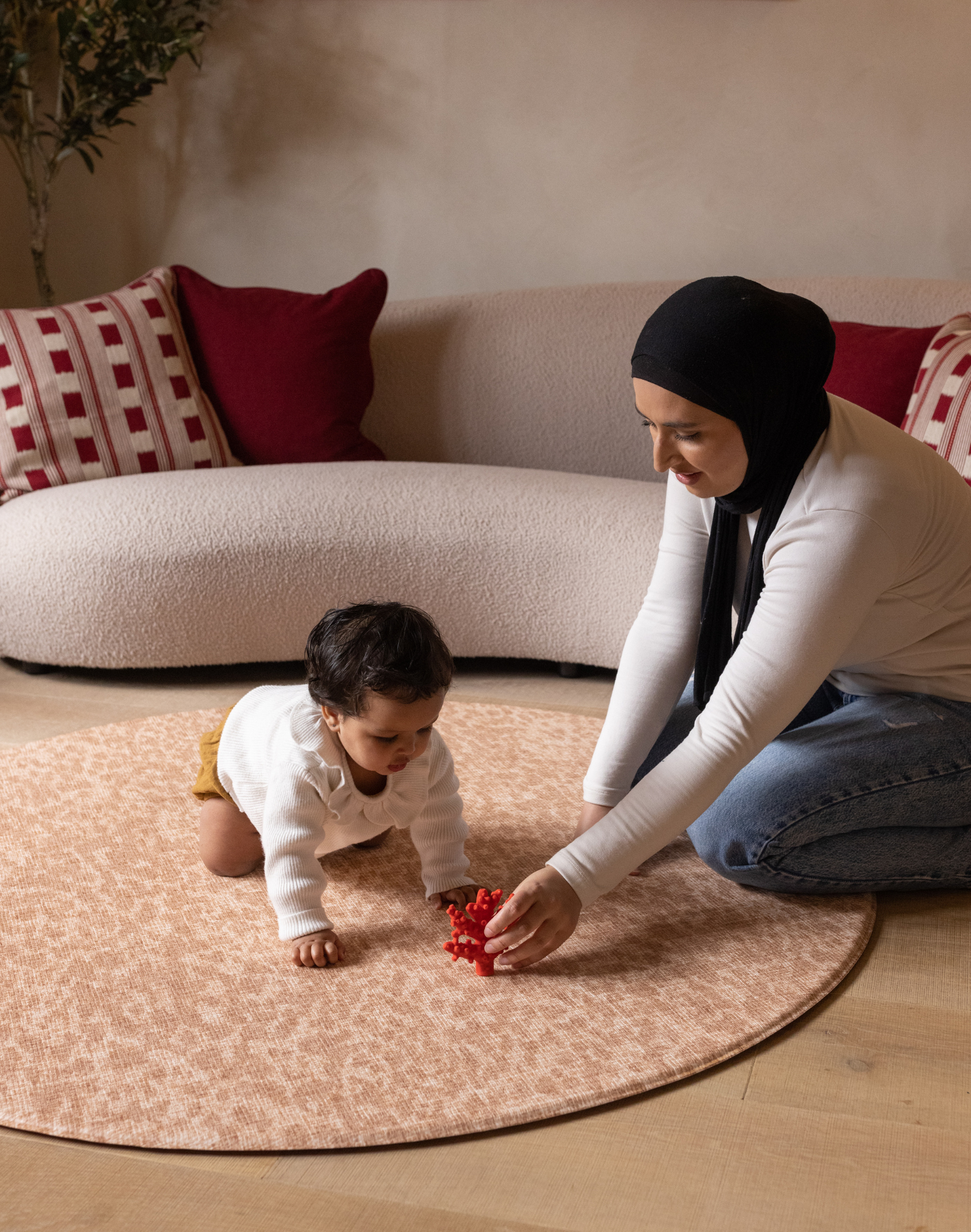 Baby and mother play on round orange play mat the Rusa with a delicate animal skin motif that looks stylish against modern furnishings