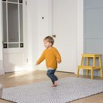 Little boy runs across the extra large playmat by totter and tumble with a polka dot design