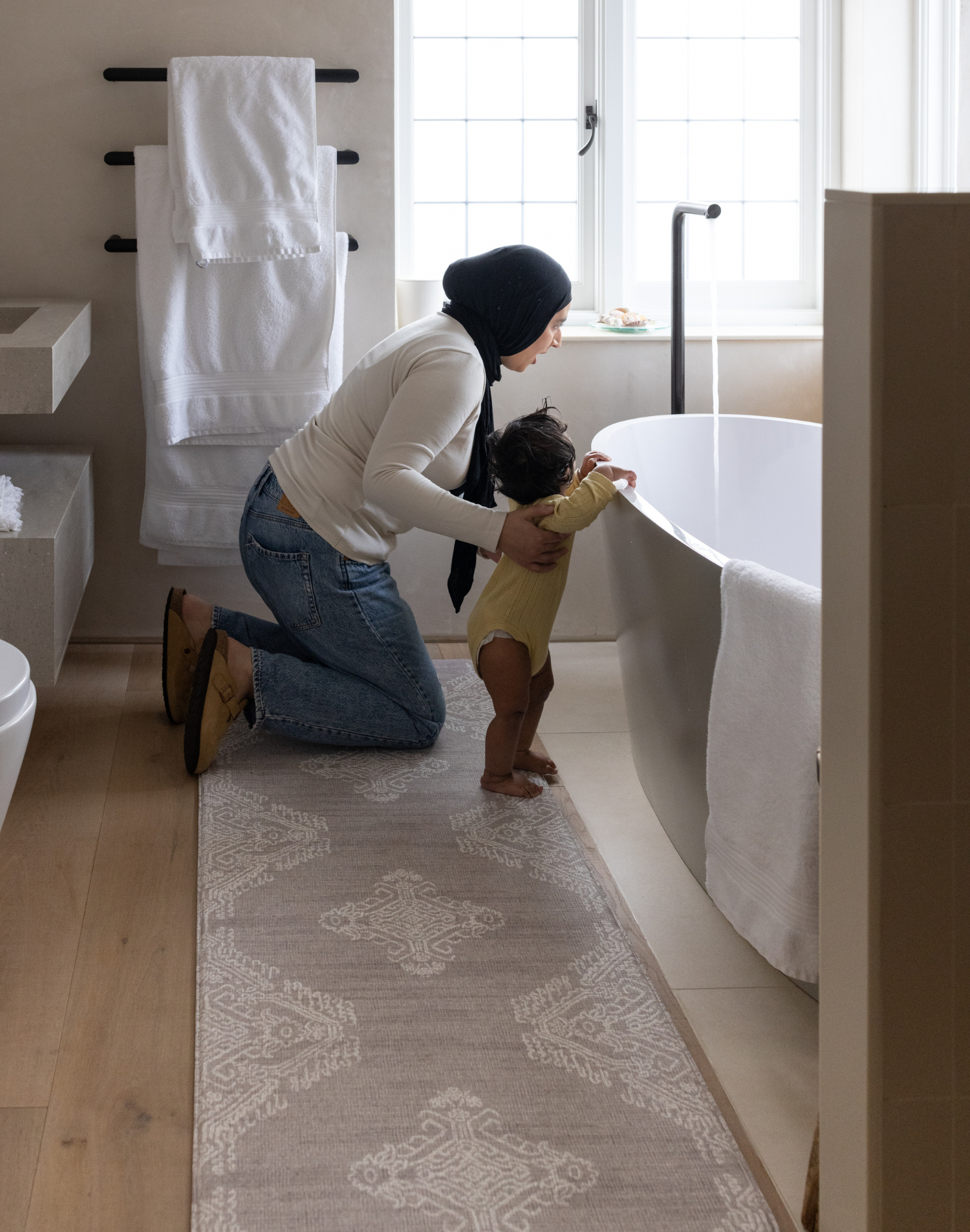 Mother and baby prepare for bath time keeping comfortable on the memory foam bath room mat the sepi with a grey design that sits subtly in modern bathroom designs also use the mat as a kitchen mat runner or exercise mat in the home