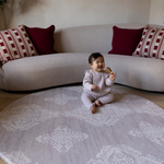 Baby sits unaided in comfort on the round sepi play mat with a gentle grey batik design that complements modern homes and thick memory foam to protect during wobbles and falls