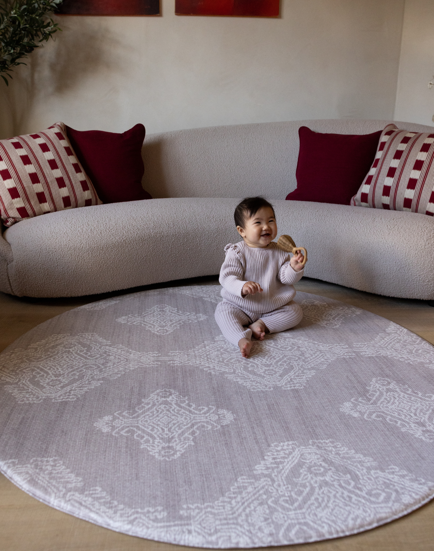 Baby sits unaided in comfort on the round sepi play mat with a gentle grey batik design that complements modern homes and thick memory foam to protect during wobbles and falls