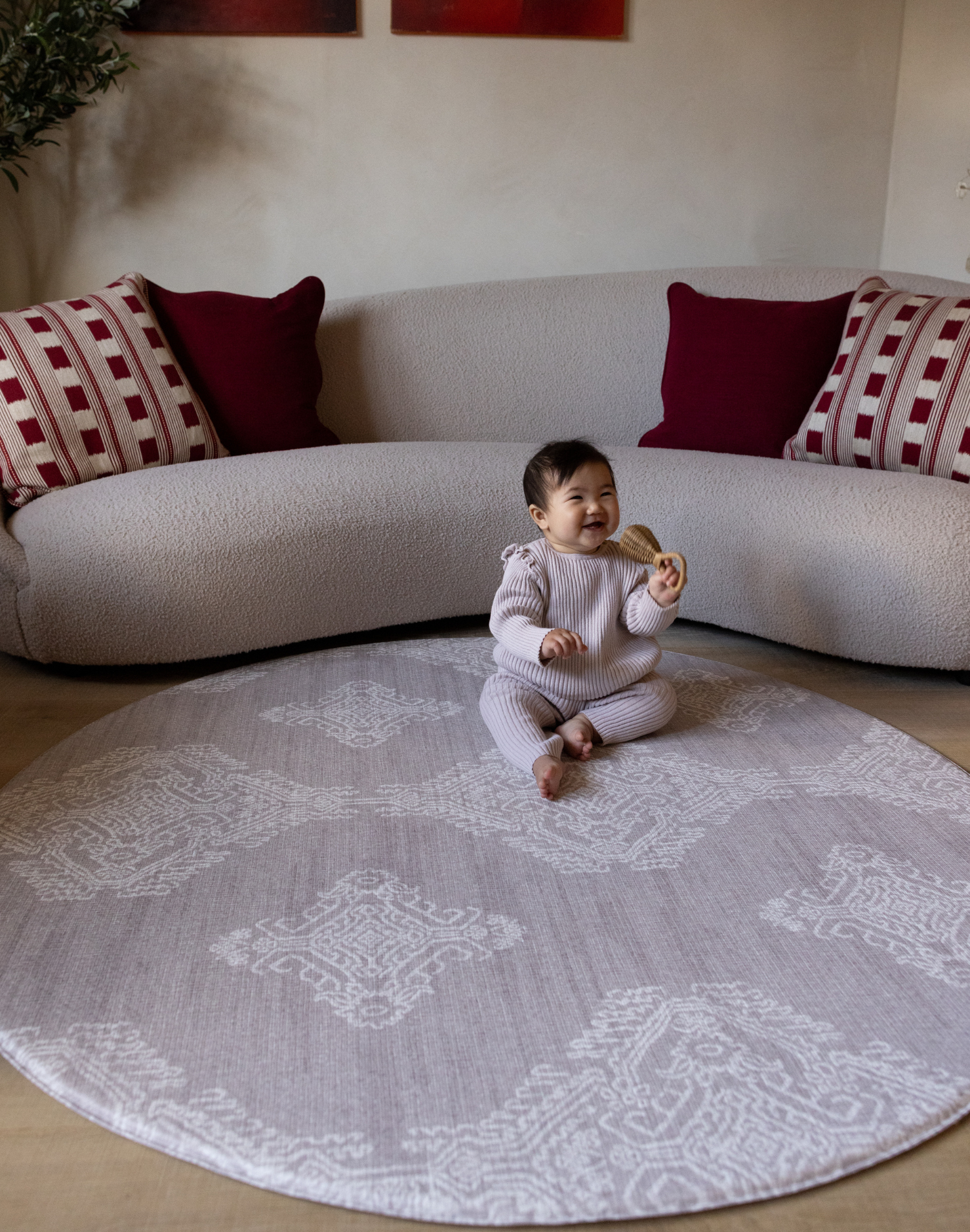 Baby sits unaided in comfort on the round sepi play mat with a gentle grey batik design that complements modern homes and thick memory foam to protect during wobbles and falls