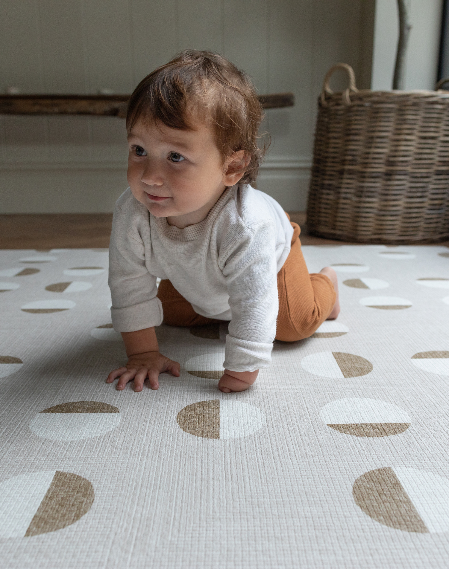 Baby crawls across neutral playmat with modern design to complement family interiors