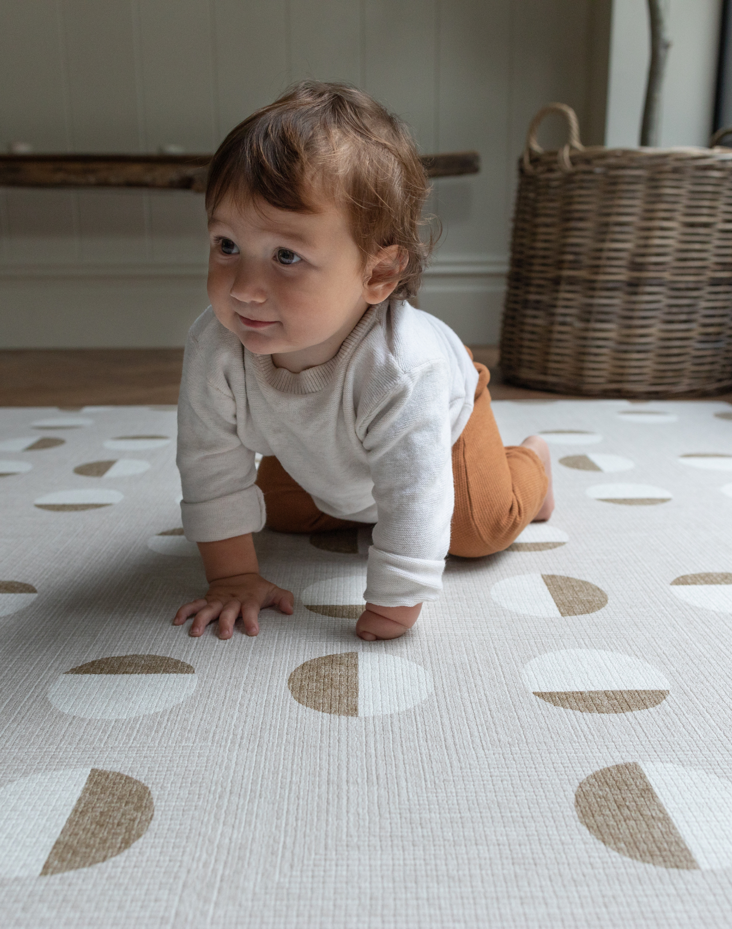 Baby crawls across neutral playmat with modern design to complement family interiors