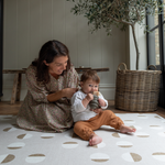Mother and toddler enjoy play time on a greige play mat with a supportive stylish design to keep everyone comfortable on the floor