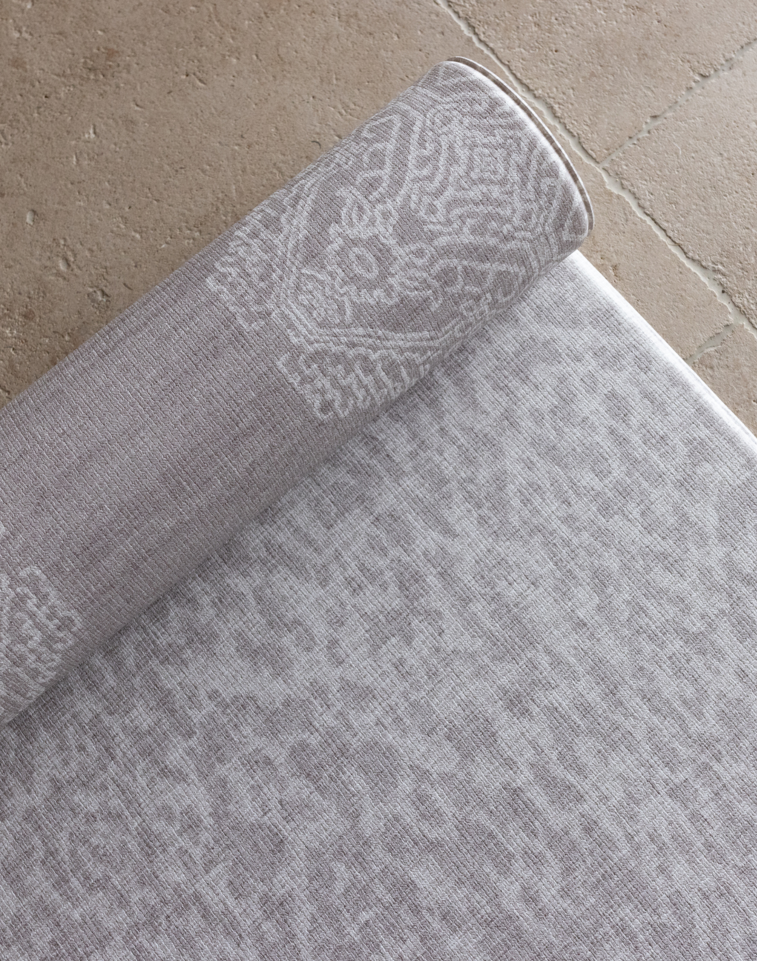 Close up of the grey animal print playmat with a textural batik inspired rug design on the rug unroll on hard wood tiled or carpeted flooring for support and comfort for the whole family