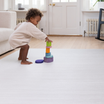 Toddler stacking wooden toys on Baby play mat with modern tan and beige gradient motif