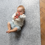 Baby plays with non toxic teething toy laying on comfortable play mat that keeps little ones off cold hard floors