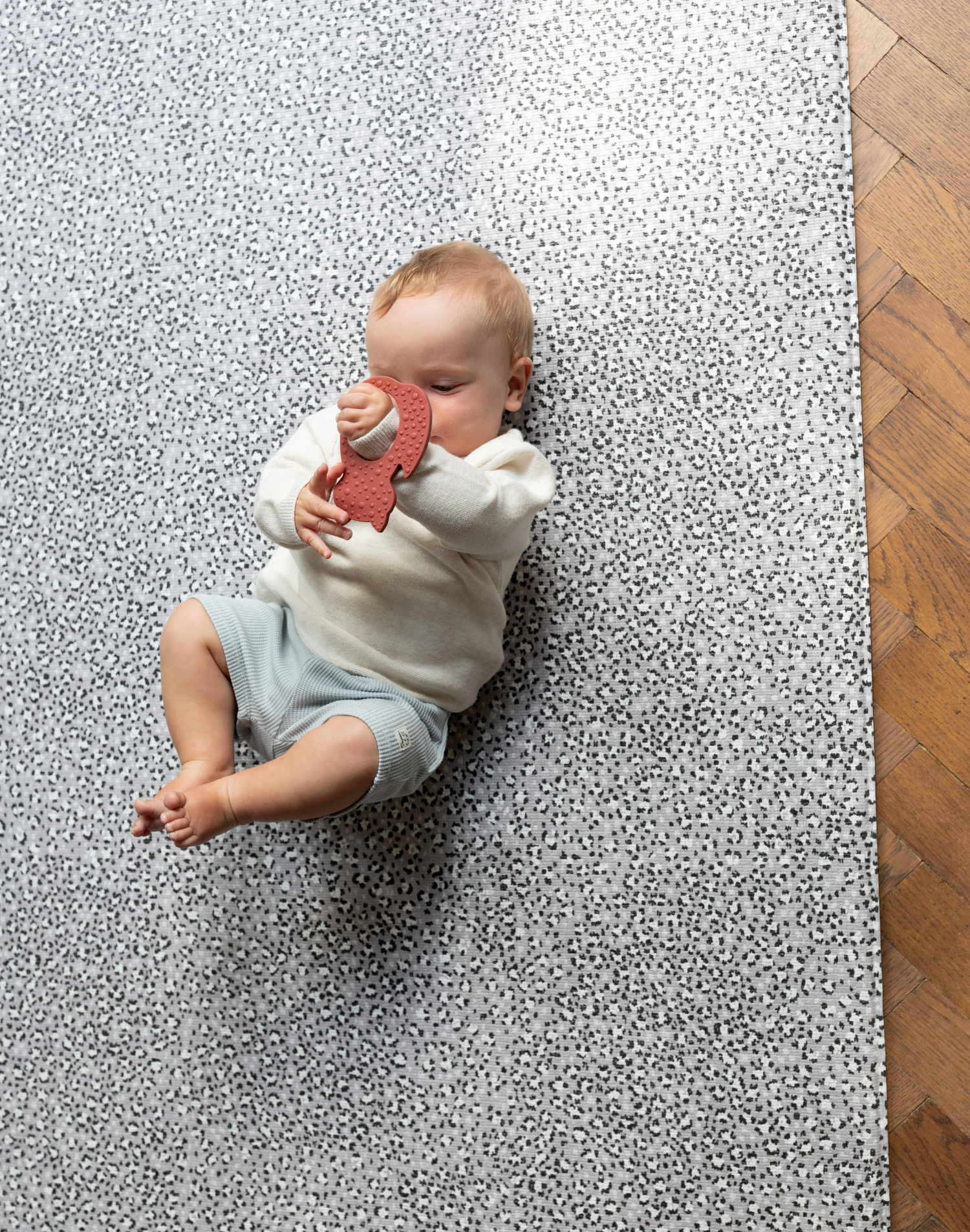 Baby plays with non toxic teething toy laying on comfortable play mat that keeps little ones off cold hard floors