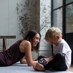 Exercising lady and boy giggle on the floor supported by leopard print playmat by totter and tumble