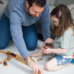 Father and daughter play together on foam grey playmat designed to look like a rug in the home while providing support