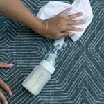 Wiping milk spill off washable totter and tumble baby play mat perfect for easy cleaning in family homes