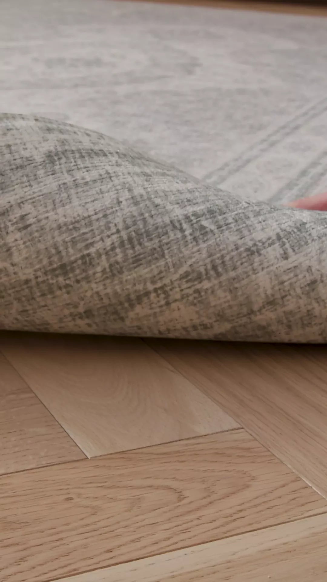 A video of a hand lifting up a rug-like extra large playmat. On the reverse we see a stylish grey patterned deign