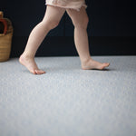 Toddler walking across Totter + Tumble's Seafarer iron blue playmat subtle pattern to fit in with your home interior
